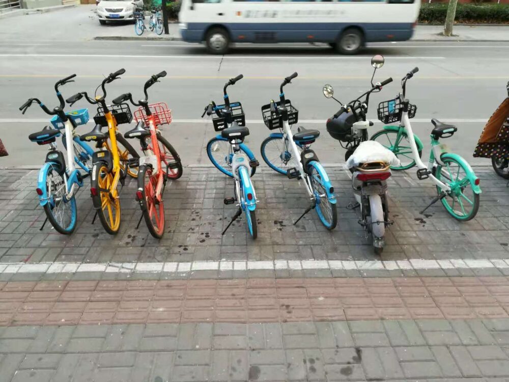 上海の街中にいろいろな種類のシェアバイクが並んでいる様子の写真